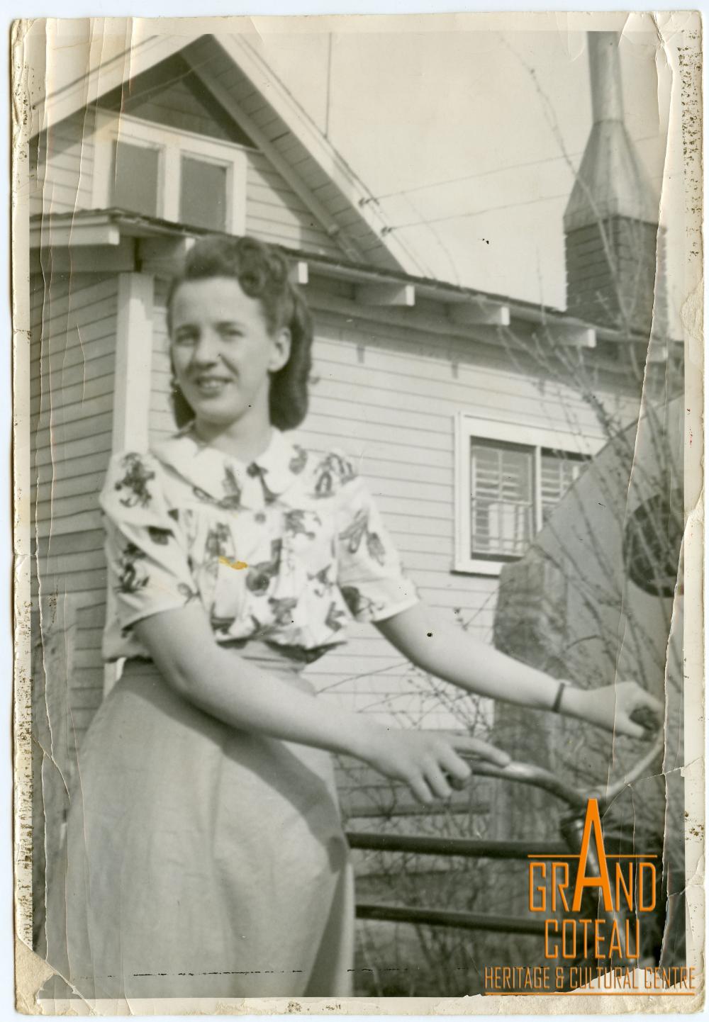 Photographic Print, unidentified woman posing with bicycle in front of house