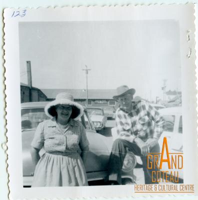 Photographic Print, unidentified man and woman standing in front of vehicle