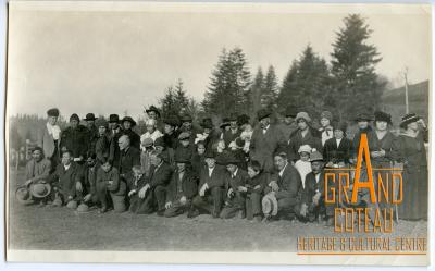 Photographic print, unidentified group of men, women and children posed outside.