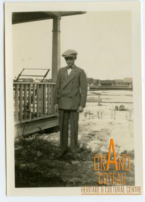 Photographic Print, unidentified young man standing beside a porch