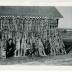 Photographic print, hunters posing with coyote pelts tacked to shed