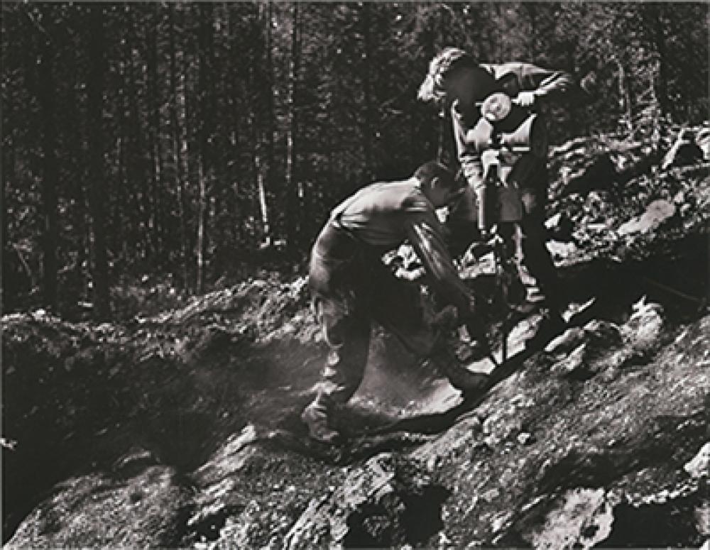 SK: Beaverlodge area - John Nesbitt, geologist-prospector-developer (with drill) is assisted by Alex Zeemel.  They are working on a claim near the Nesbitt-Labine uranium mines property